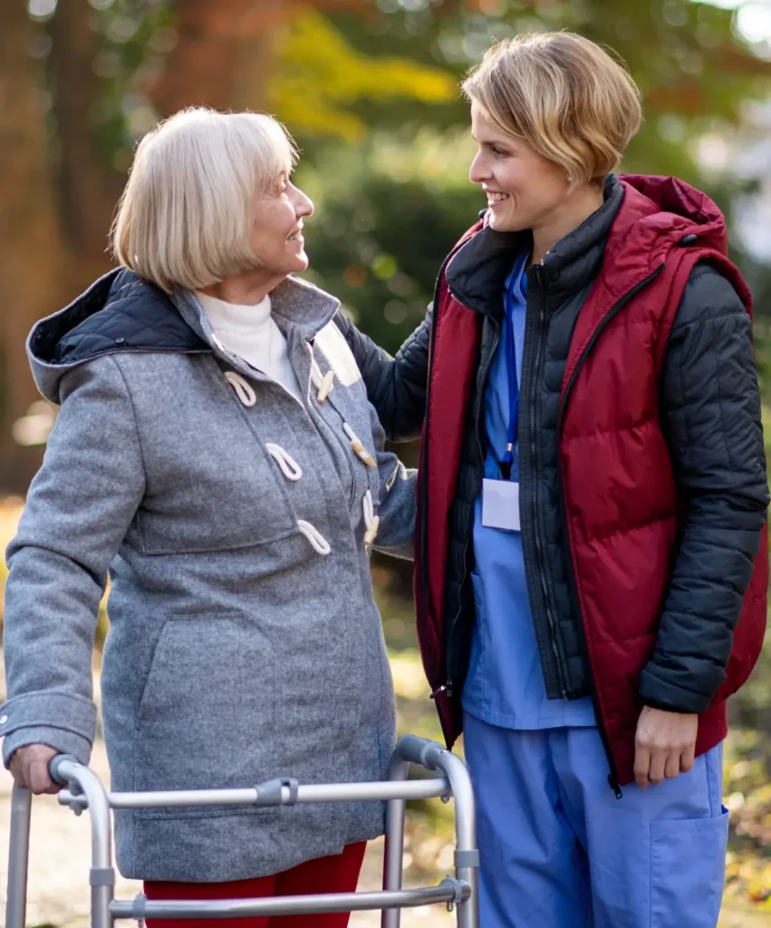 Compassionate in-home caregiver assisting a senior woman with a walking frame outdoors in Carroll County, Maryland.
