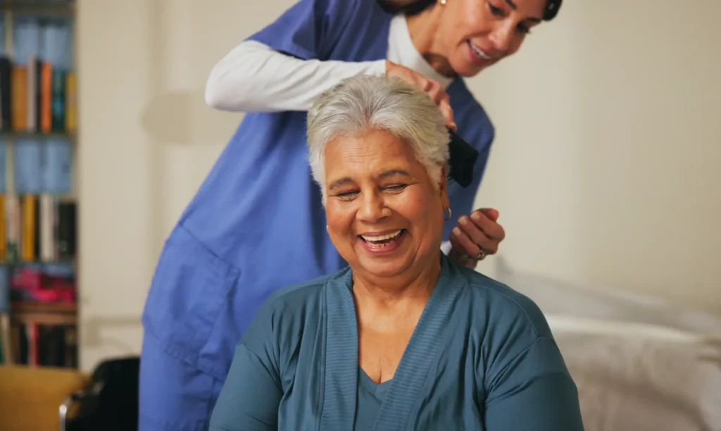 A compassionate in-home caregiver in Maryland gently brushes the hair of a senior woman, providing essential personal care assistance.